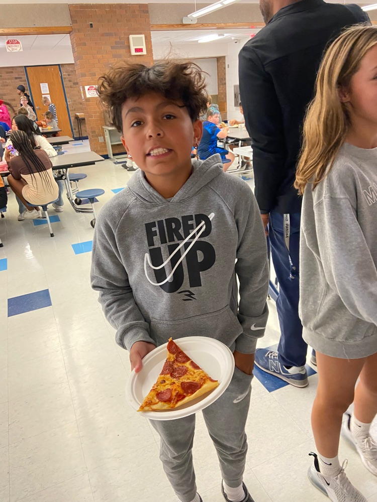 student smiling holding plate of pizza