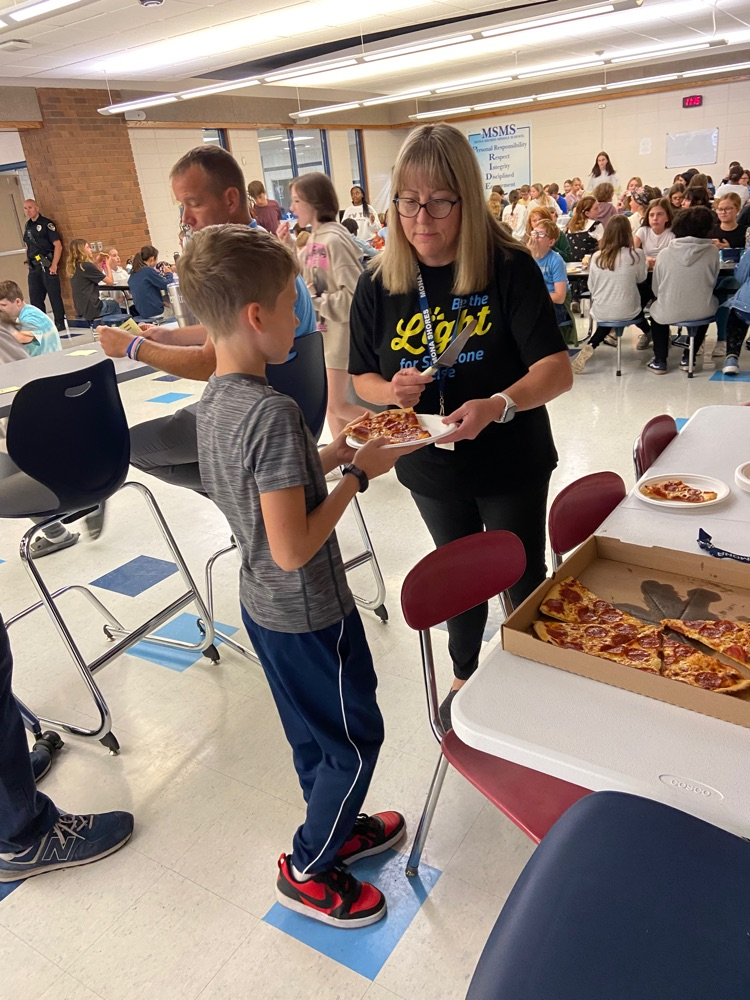 student receiving pizza reward from staff 