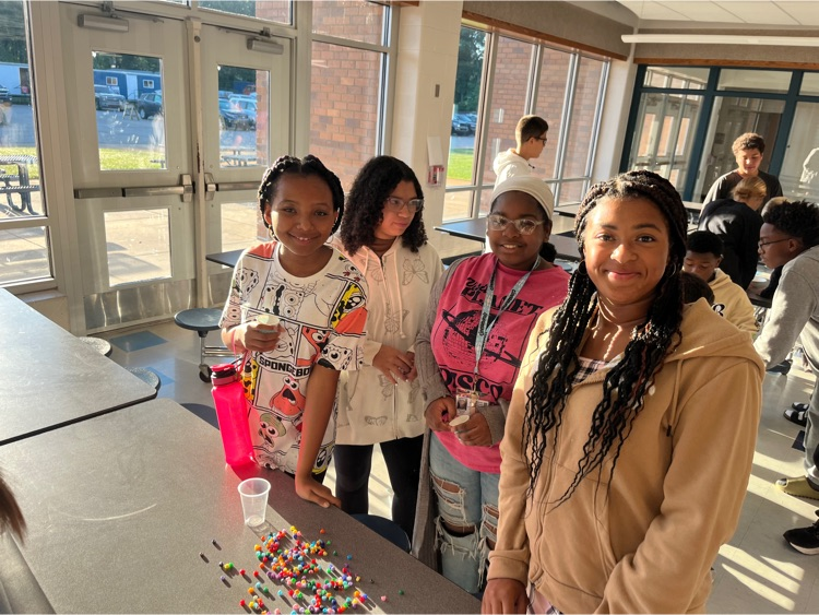 4 students at table with bracelet materials