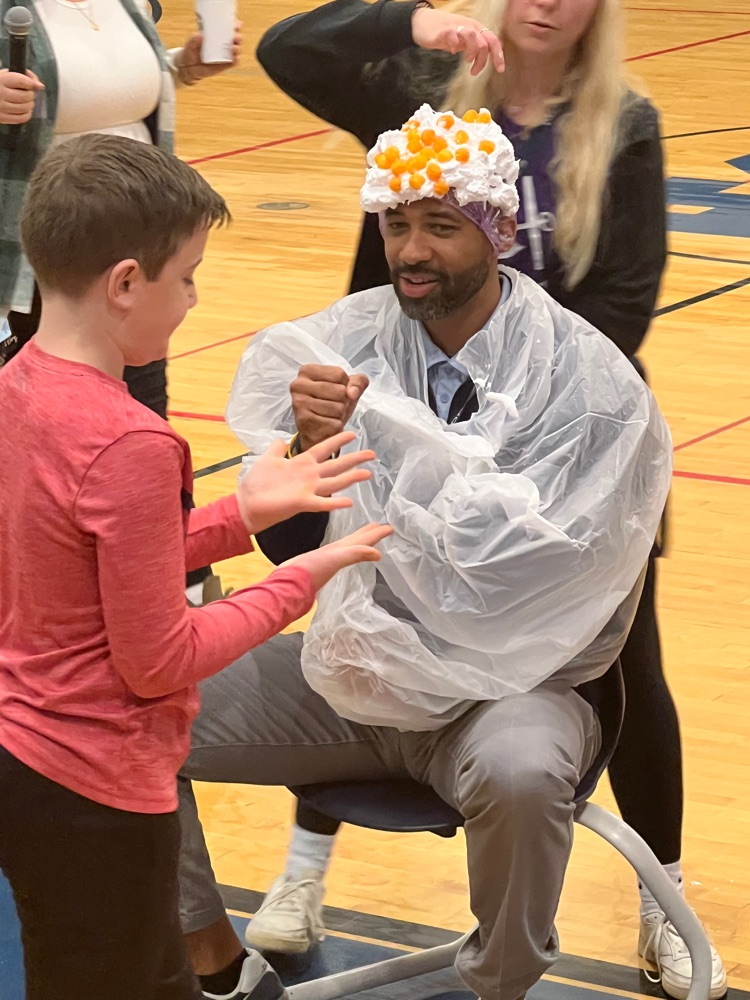 Student and staff counting cheese balls on Mr. Burrel’s head