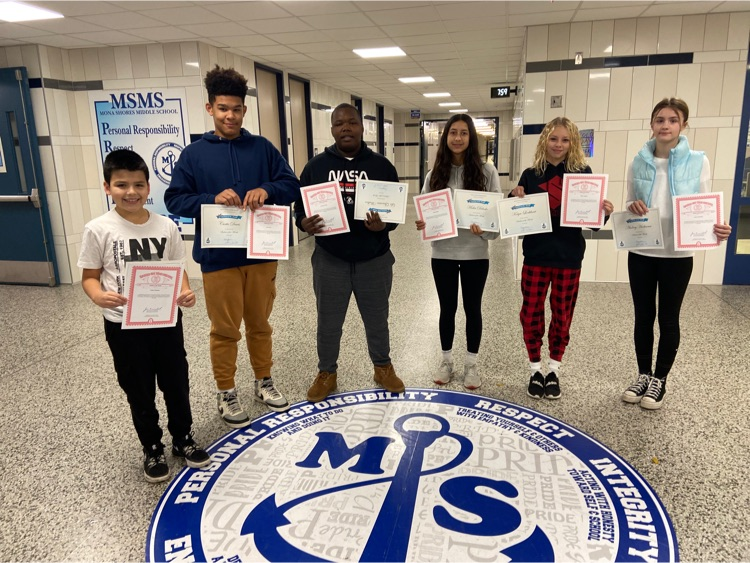 students standing in hallway with student of the month certificates
